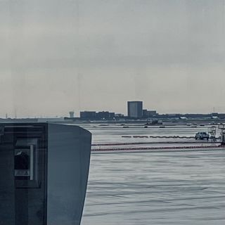 flat tarmac with buildings and vehicles in the distance, large machinery in foreground